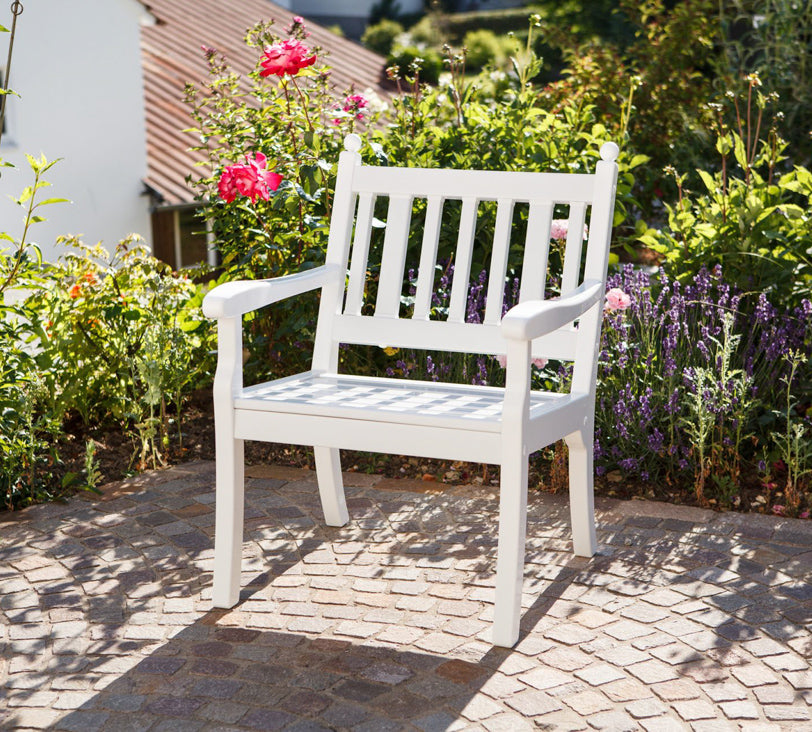 Weißer Stuhl "Hohenzollern" vor Blumenbeet in Gartenlandschaft, im Hintergrund unscharf erkennbare Häuser