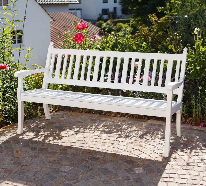 Weiße Bank "Hohenzollern" vor Blumenbeet in Gartenlandschaft, im Hintergrund unscharf erkennbare Häuser