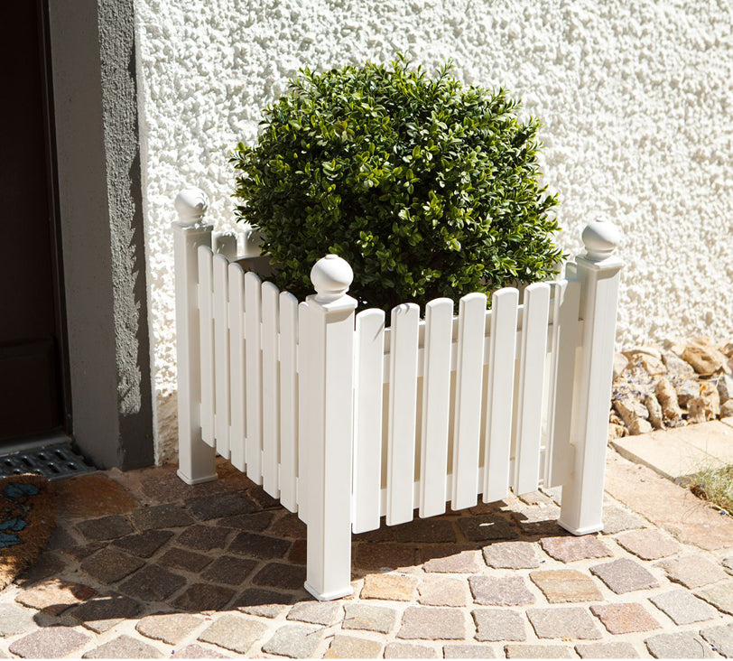 Pflanzkasten Landhaus in Weiß vor einer Hauswand auf einem Steinboden mit einem Busch darin