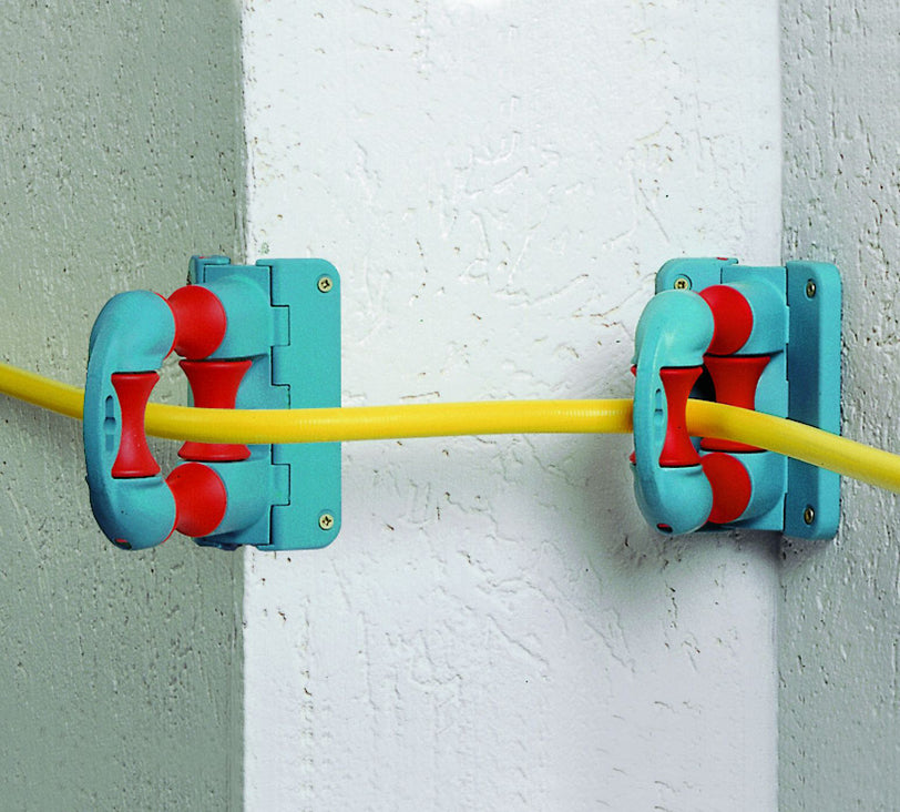 Quadrofix im Einsatz befestigt an einer Wand und durch diese läuft ein Schlauch