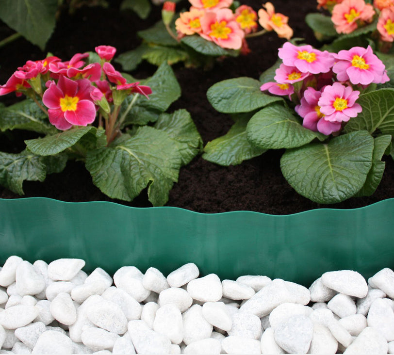 Rasenkante im Einsatz trennt ein Blumenbeet und eine Schicht weißer steine.